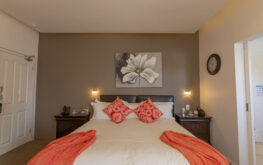 View of the bed with orange pillows and wall frame above