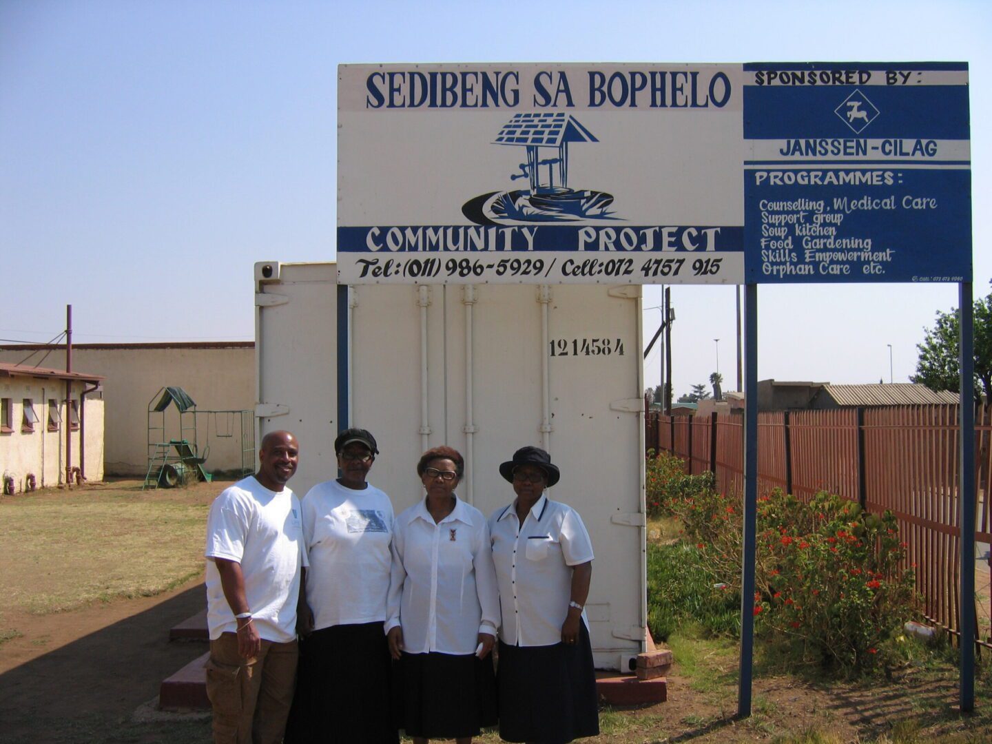 Four people standing in front of a sign.