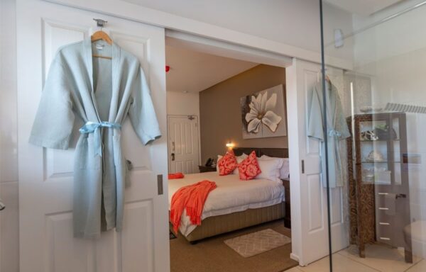 A bedroom with a bed and robe hanging on the wall.