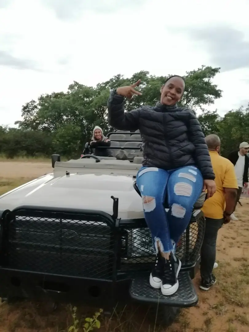 A woman sitting on the hood of a truck.