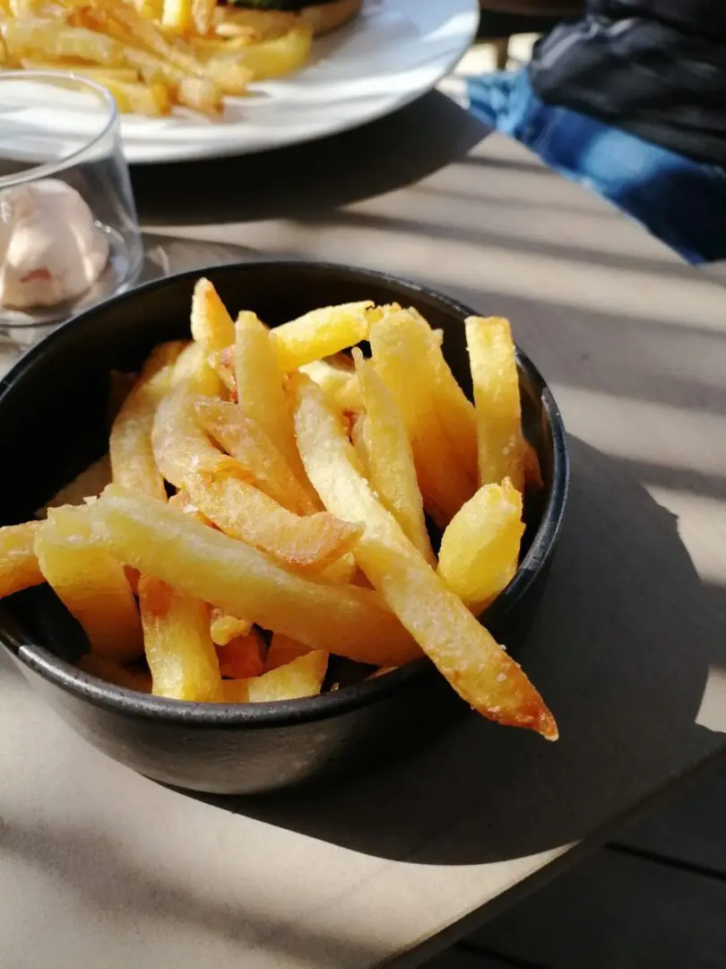 A black bowl of french fries on top of a table.