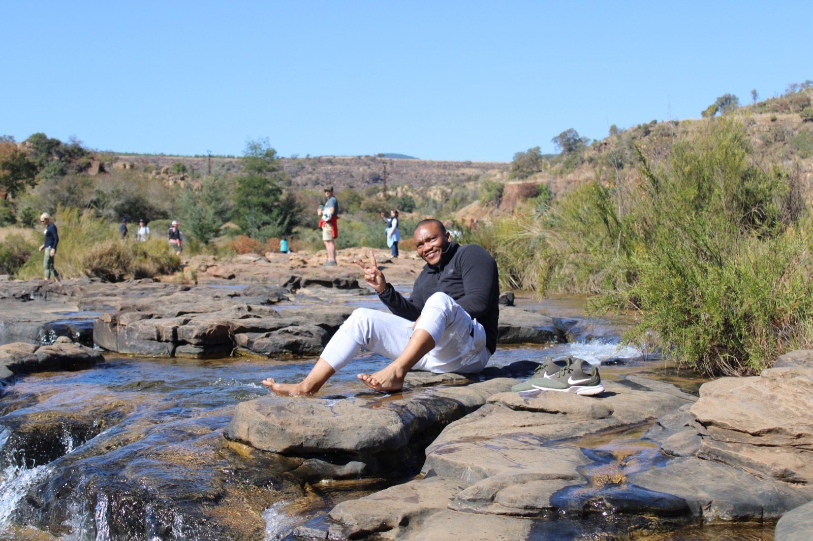A man sitting on top of rocks in the water.