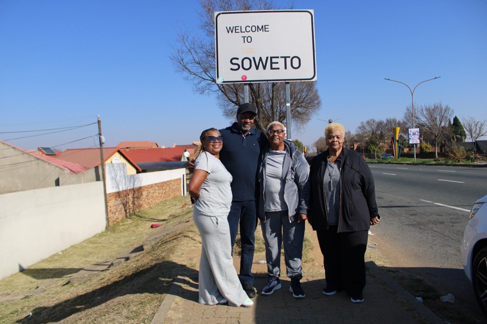 A group of people standing under a welcome to soweto sign.
