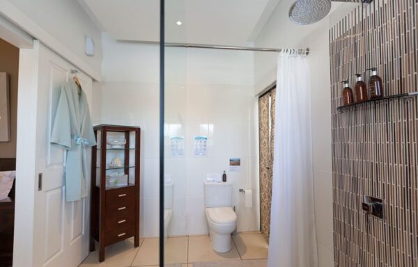 A bathroom with glass shower door and toilet.
