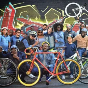 A group of people with bikes in front of a wall.