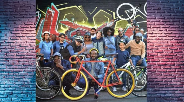 A group of people with bikes in front of a wall.