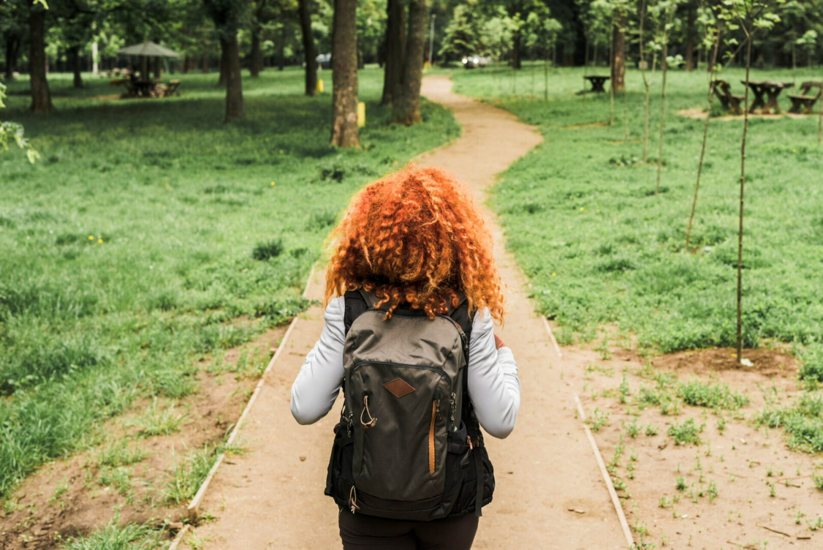 A person with red hair is walking down the path