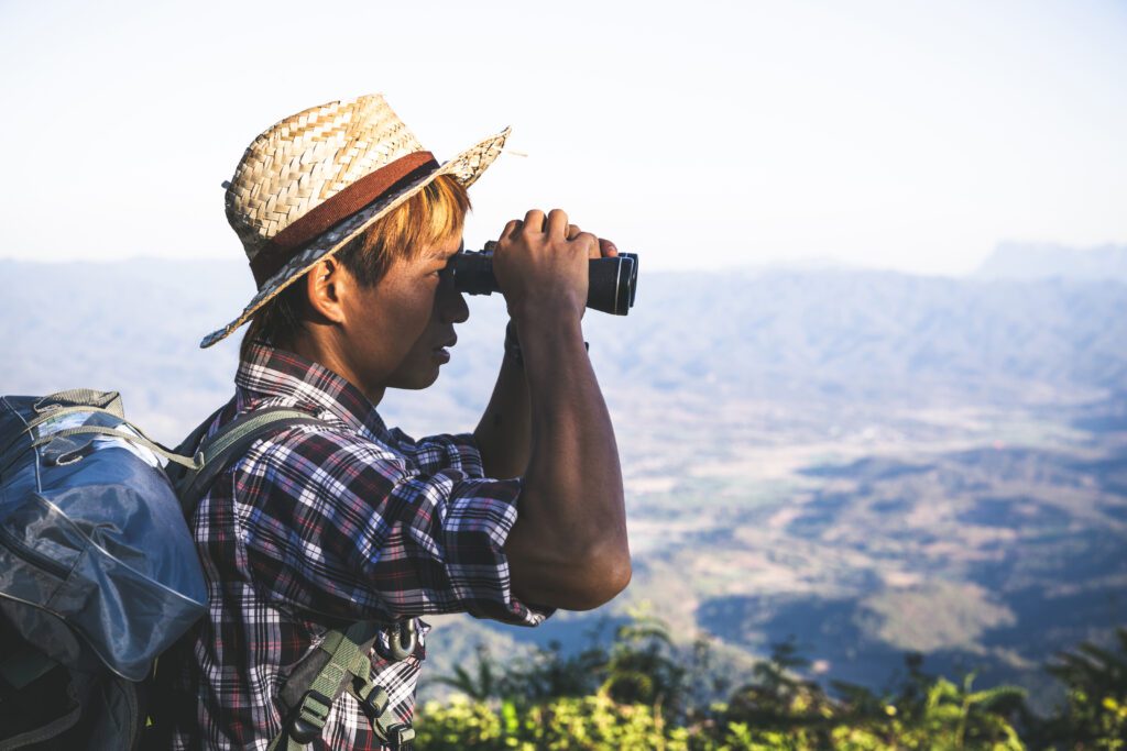 Hiker with binoculars overlooking mountain landscape